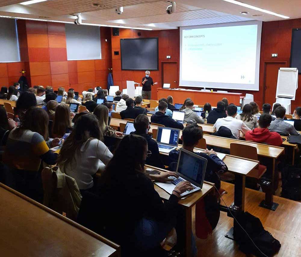 Des étudiants avec leurs ordinateurs pendant un cours en amphithéâtre.