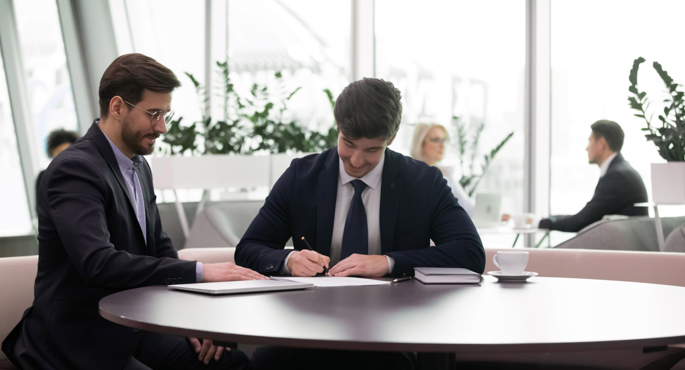 Deux professionnels échangent autour de documents dans un espace de travail lumineux.