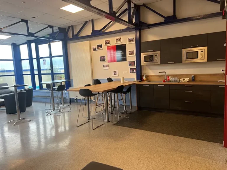 Un espace convivial de campus avec des tables, des chaises et une cuisine partagée.