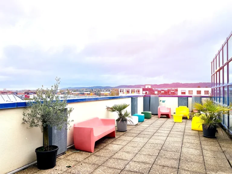 Une terrasse de campus avec des tables et des chaises colorées.