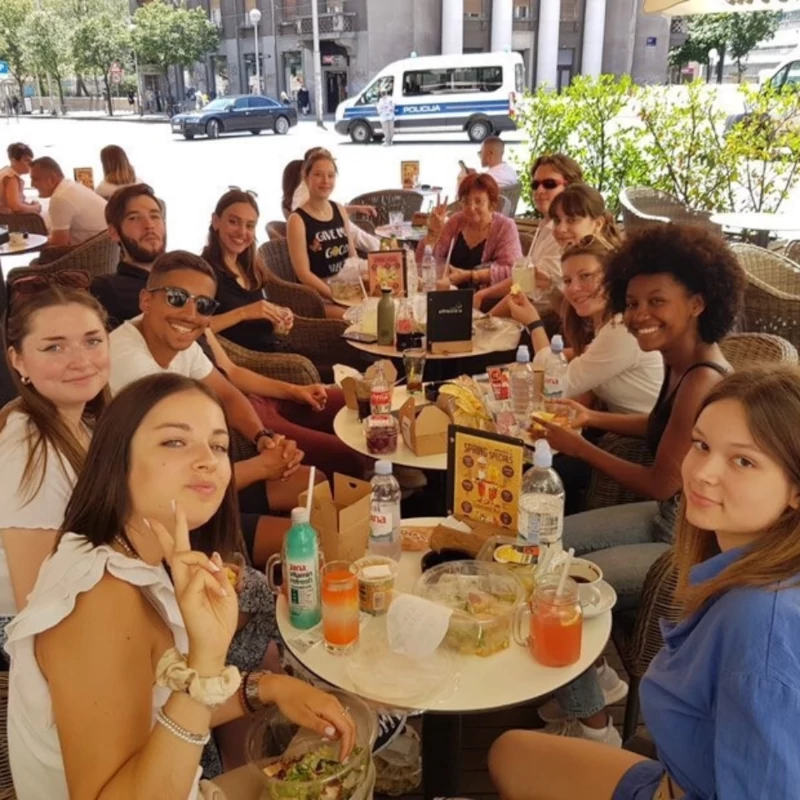 Des étudiants partagent un moment convivial autour d’une table en terrasse.