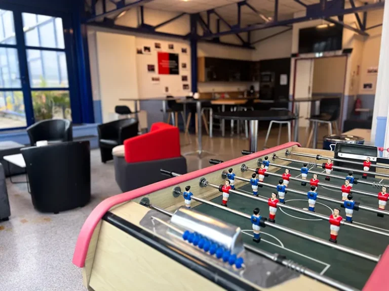 Un espace de détente sur un campus, avec des tables et un baby-foot.