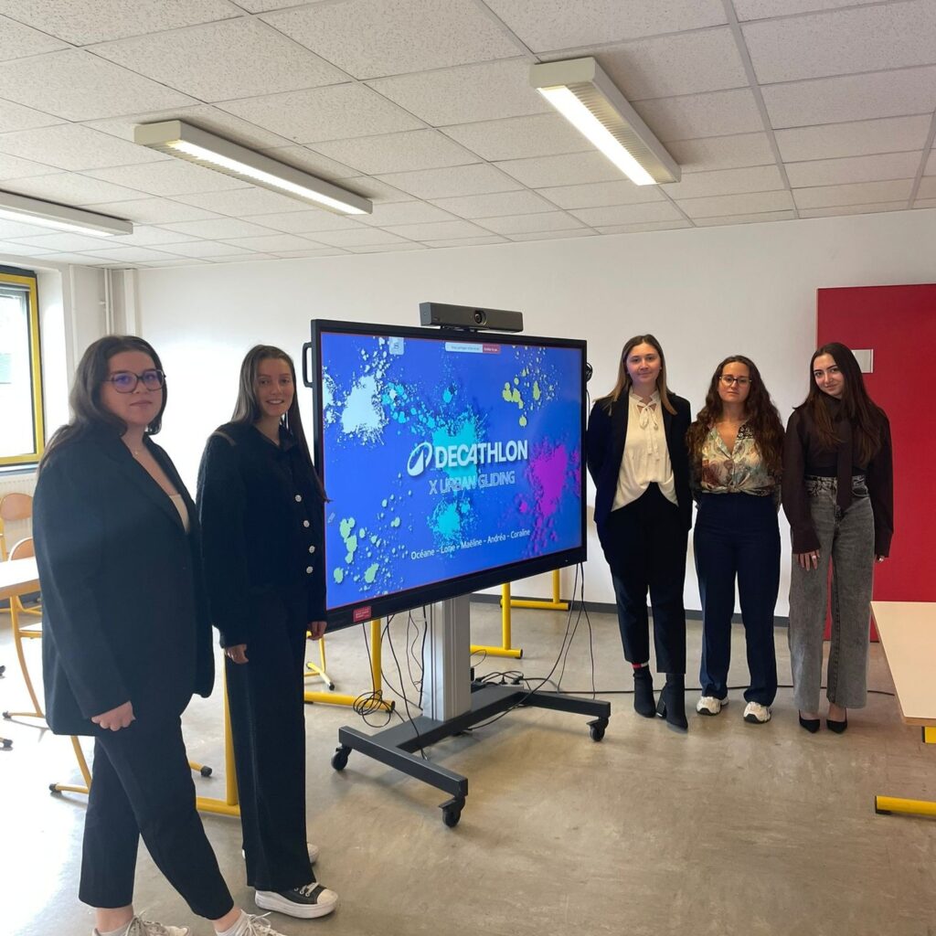 Cinq étudiantes présentent un projet collectif devant un écran.